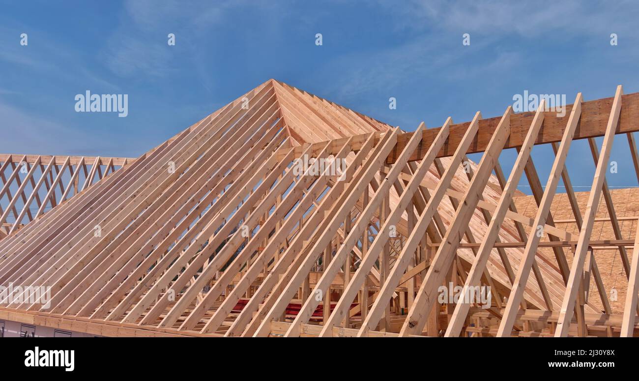 Wooden roof truss framing under construction in new home Stock Photo