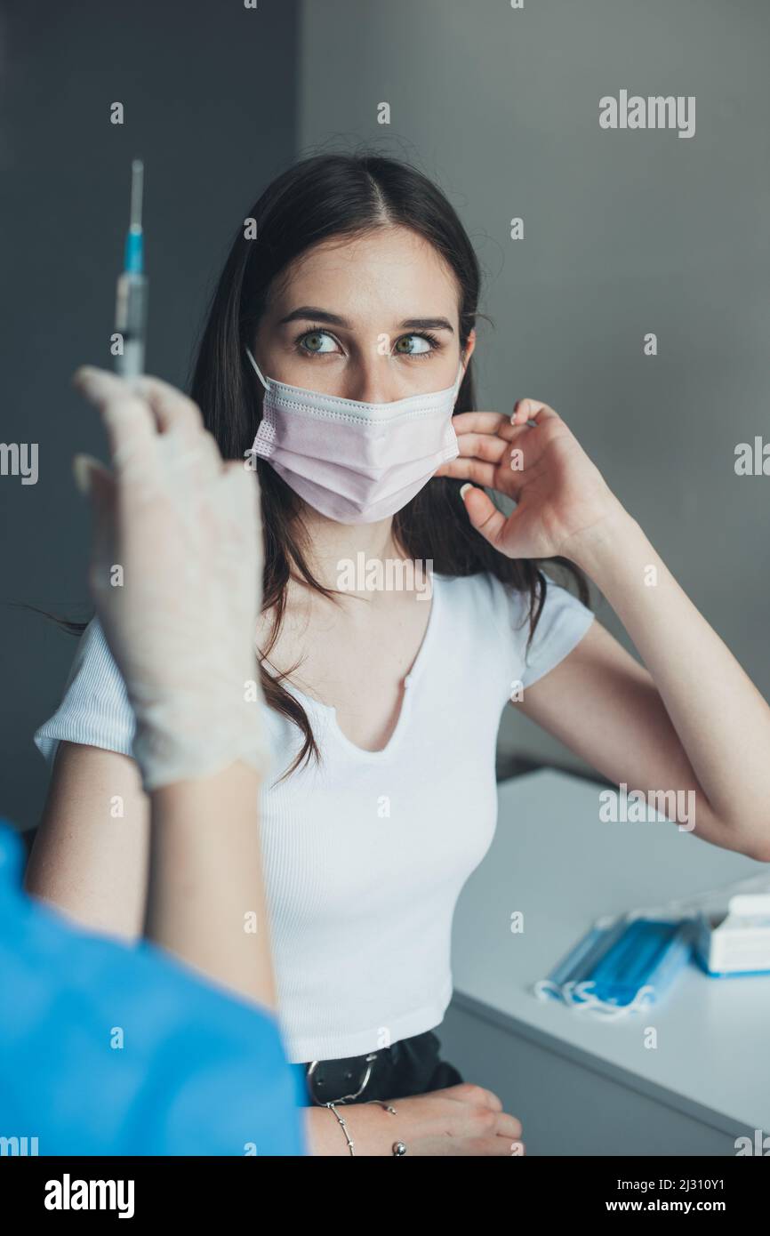 Medical assistant preparing an intramuscular injection of a vaccine for a scared girl. Virus protection. Medicine, vaccination, immunization and Stock Photo