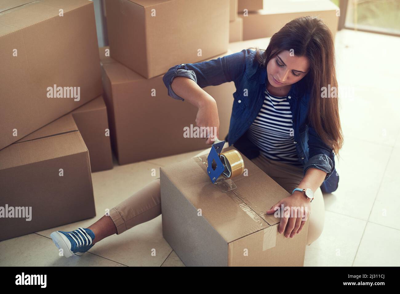 Sealing the last of her belongings. Shot of a young woman packing boxes