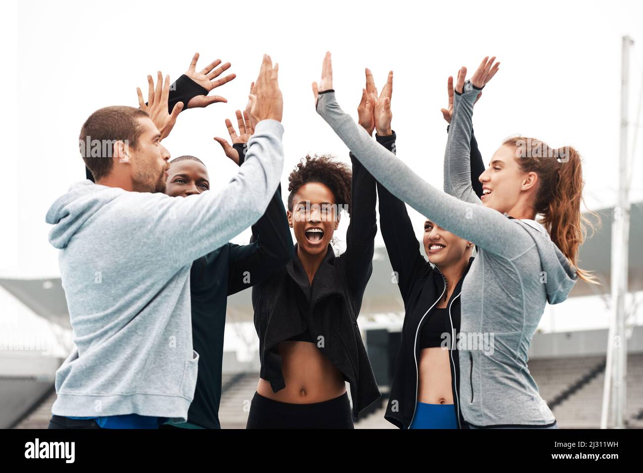 Lets go team. Cropped shot of a diverse group of athletes standing and giving each other a high five after a track session. Stock Photo