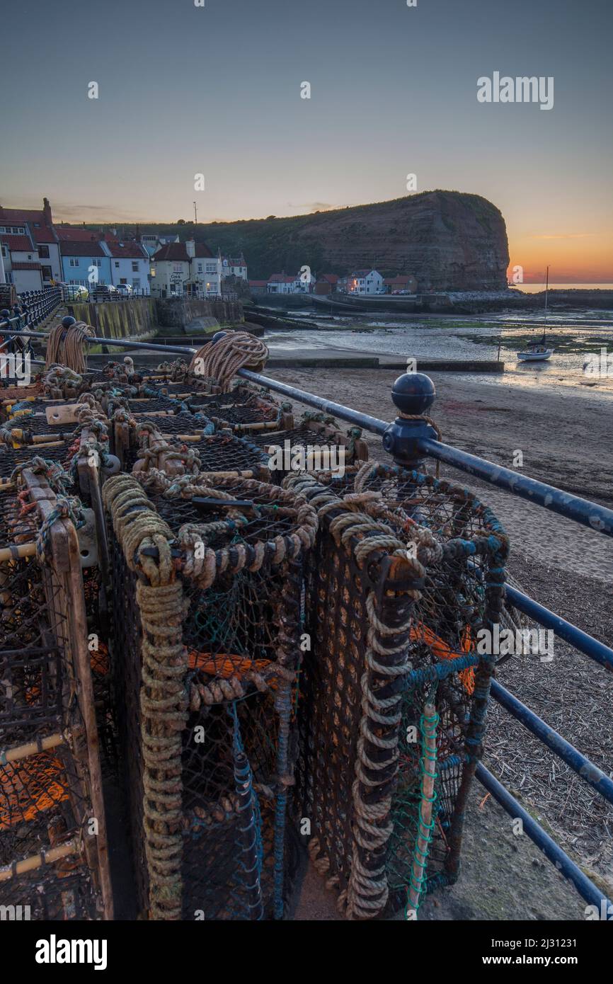 Evening view of small port town of Staithes, Yorkshire, England, UK. In the foreground lobster cages on railings. Stock Photo
