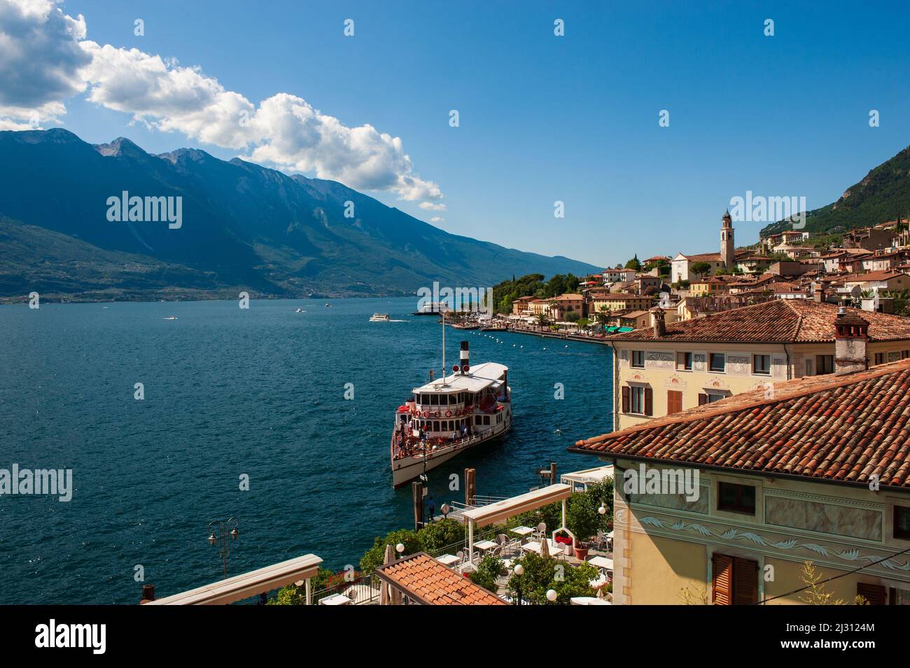 A ship full of tourists docks in Limone del Garda on the lake of the same name, on a sunny day. Brescia. Italy Stock Photo