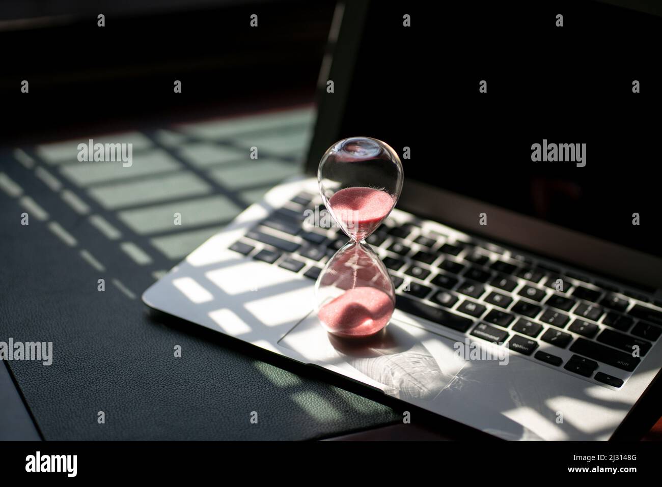 Hourglass sand timer on top of laptop. Passing time, countdown or
