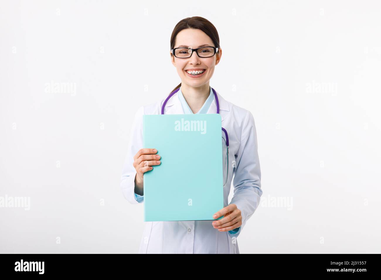 Cheerful young female doctor holding a folder in her hand and gesturing to copyspace. Stock Photo