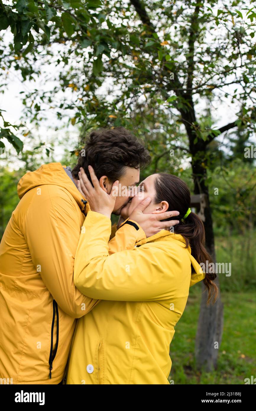 A married couple in yellow raincoats in the rain in their backyard ...