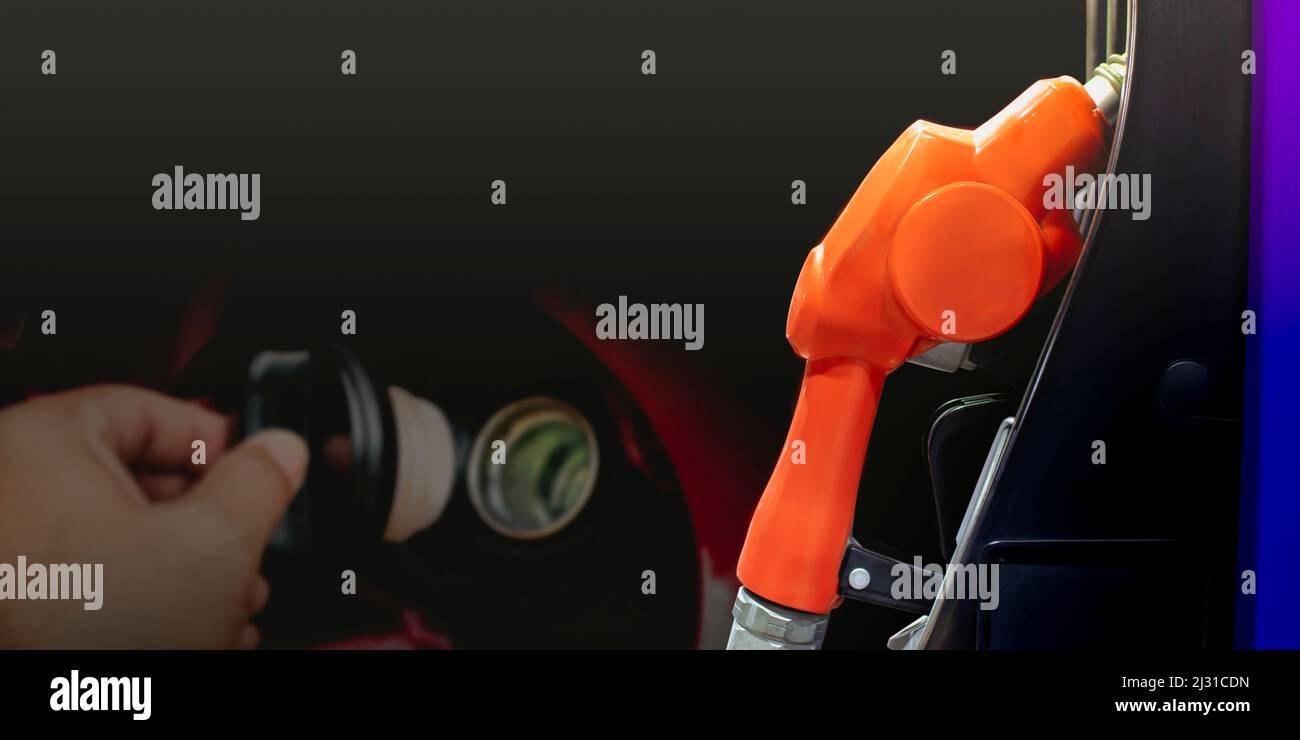 Fuel nozzle on the dispenser pump in the petrol service station on a black background and a open the fuel cap double exposure backdrop,copy space Stock Photo