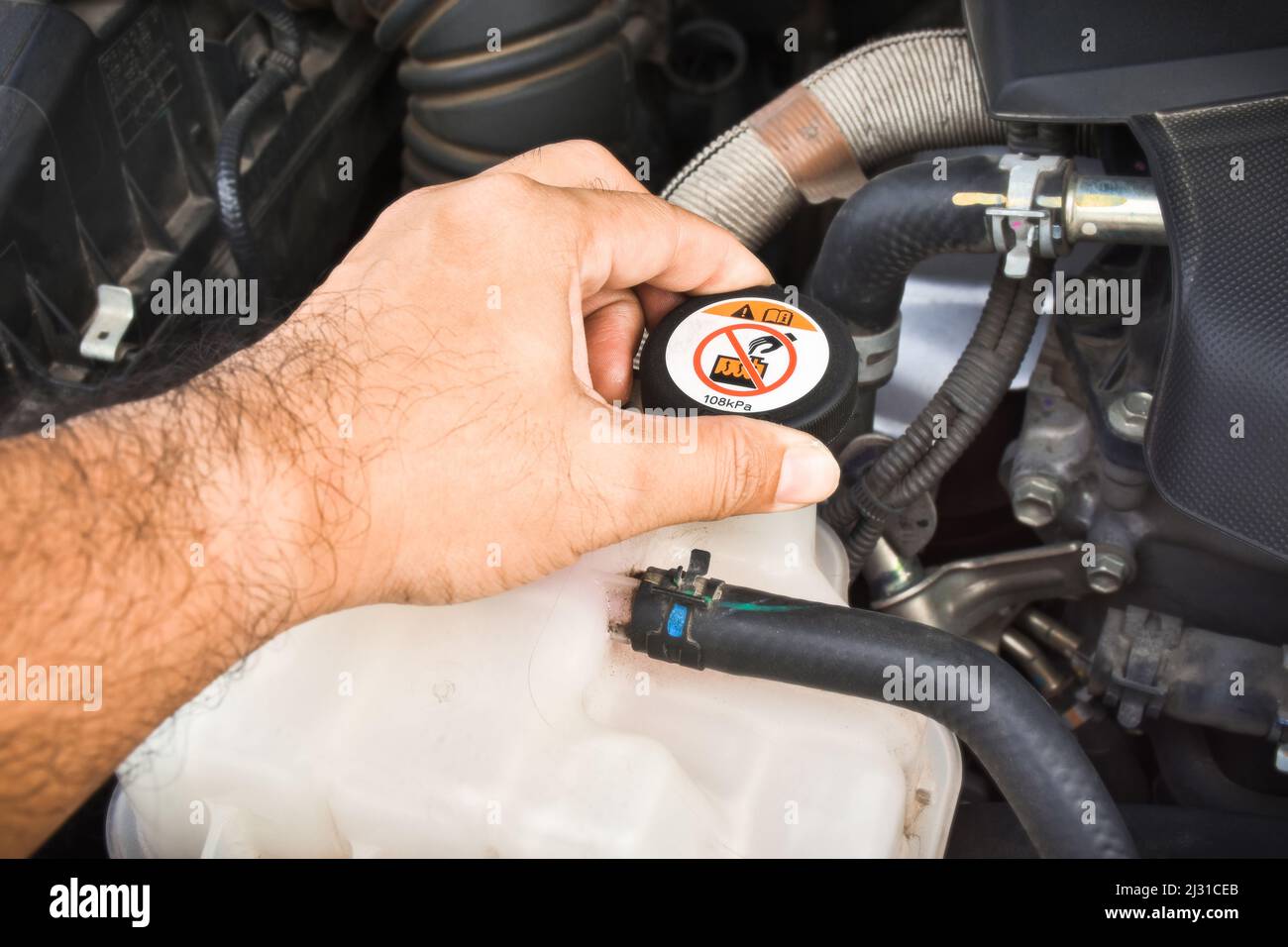Mechanic hand is opened coolant reservoir cap of the car radiator Stock