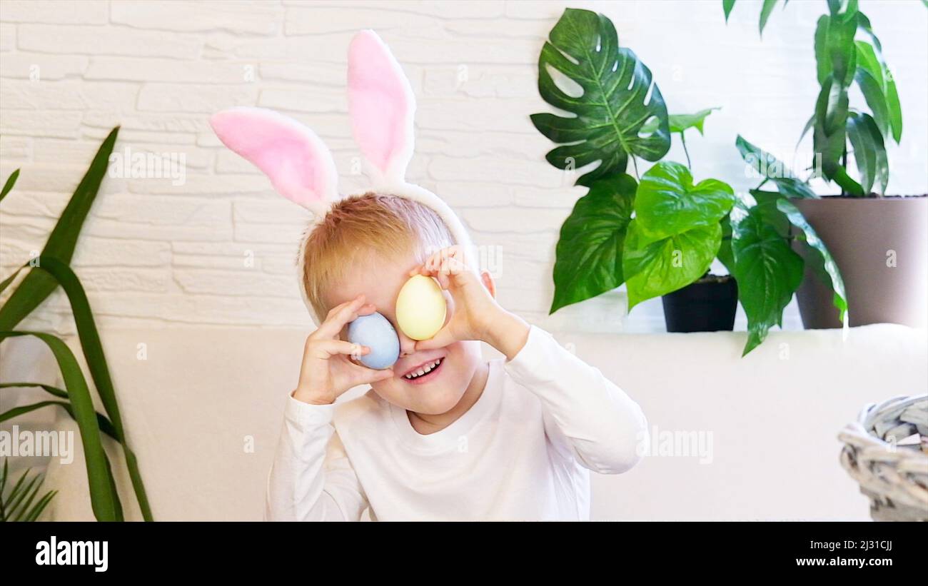 Funny happy child boy with easter eggs and bunny ears dancing. Easter concept, happy childhood. Easter Egg Hunt. Slow motion. Stock Photo
