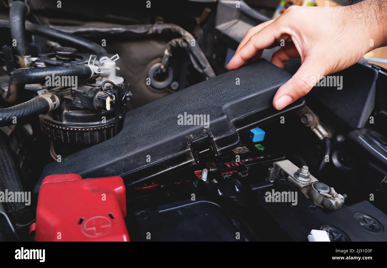 A mechanic hand is removing the fuse box from the automobile. Stock Photo