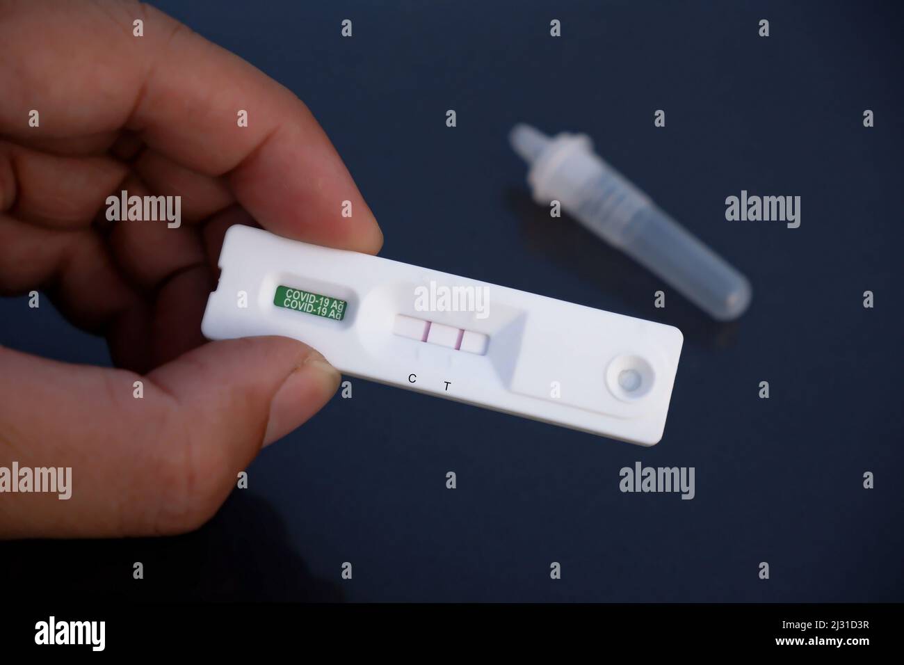 Human hand displays a Covid-19 positive result cassette from a rapid ...