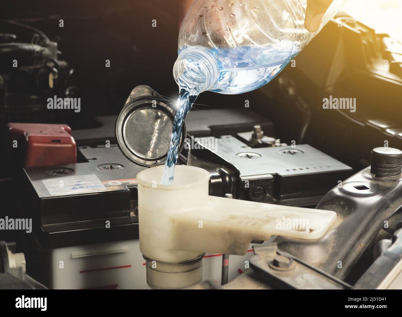 A mechanic hand was putting clean water into the car engine windshield