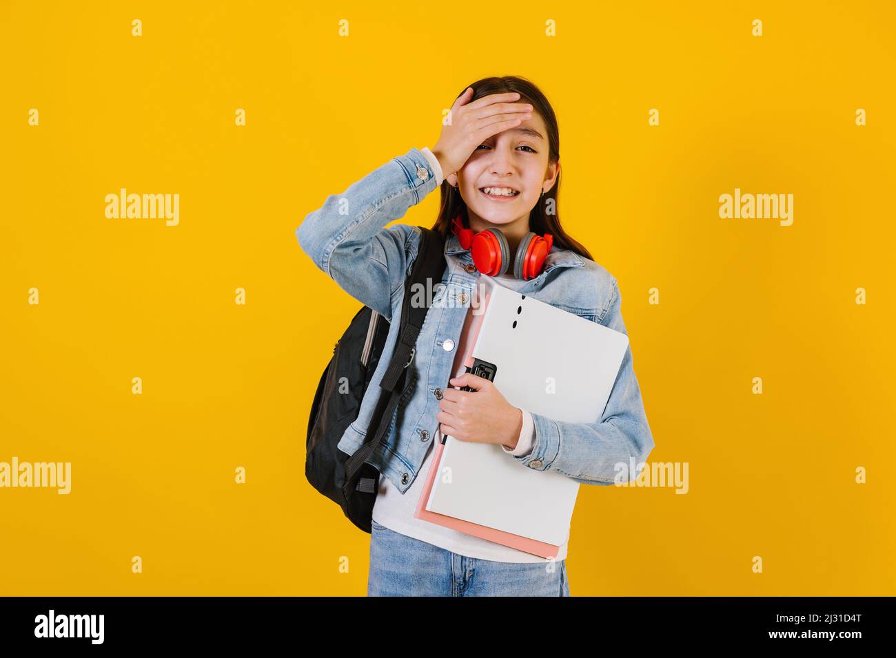 portrait of young hispanic child teen girl student with worried expression on a yellow background in Mexico Latin America Stock Photo
