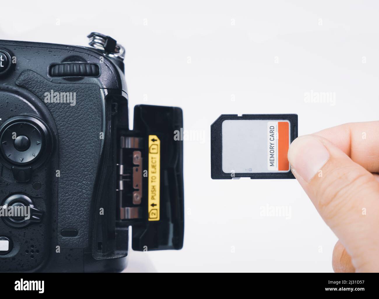 Photographer hand insert memory SD card to memory slot of the digital DSLR camera,isolated on white background Stock Photo