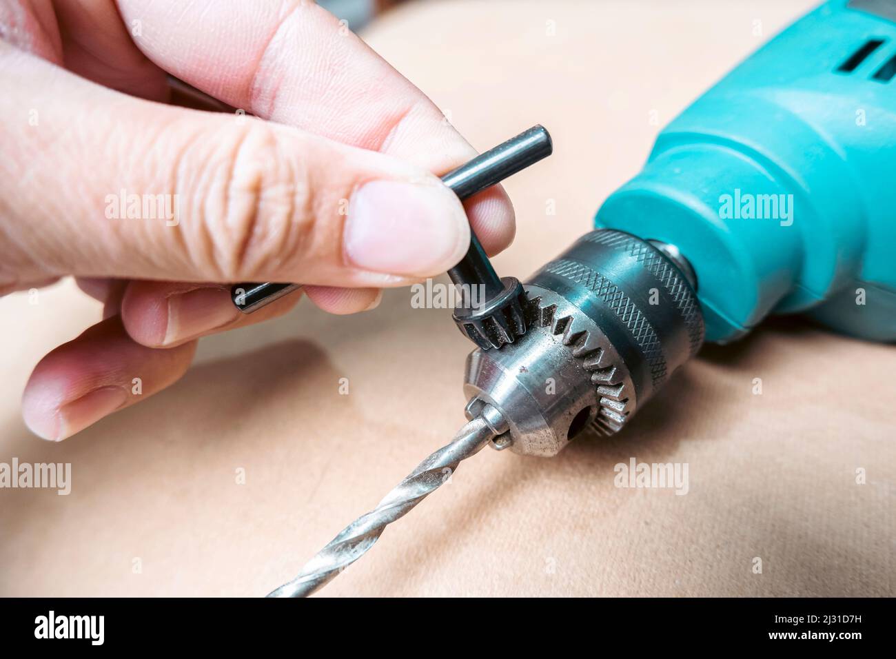 A mechanic is inserting the drill bit into an electric drill and fasten