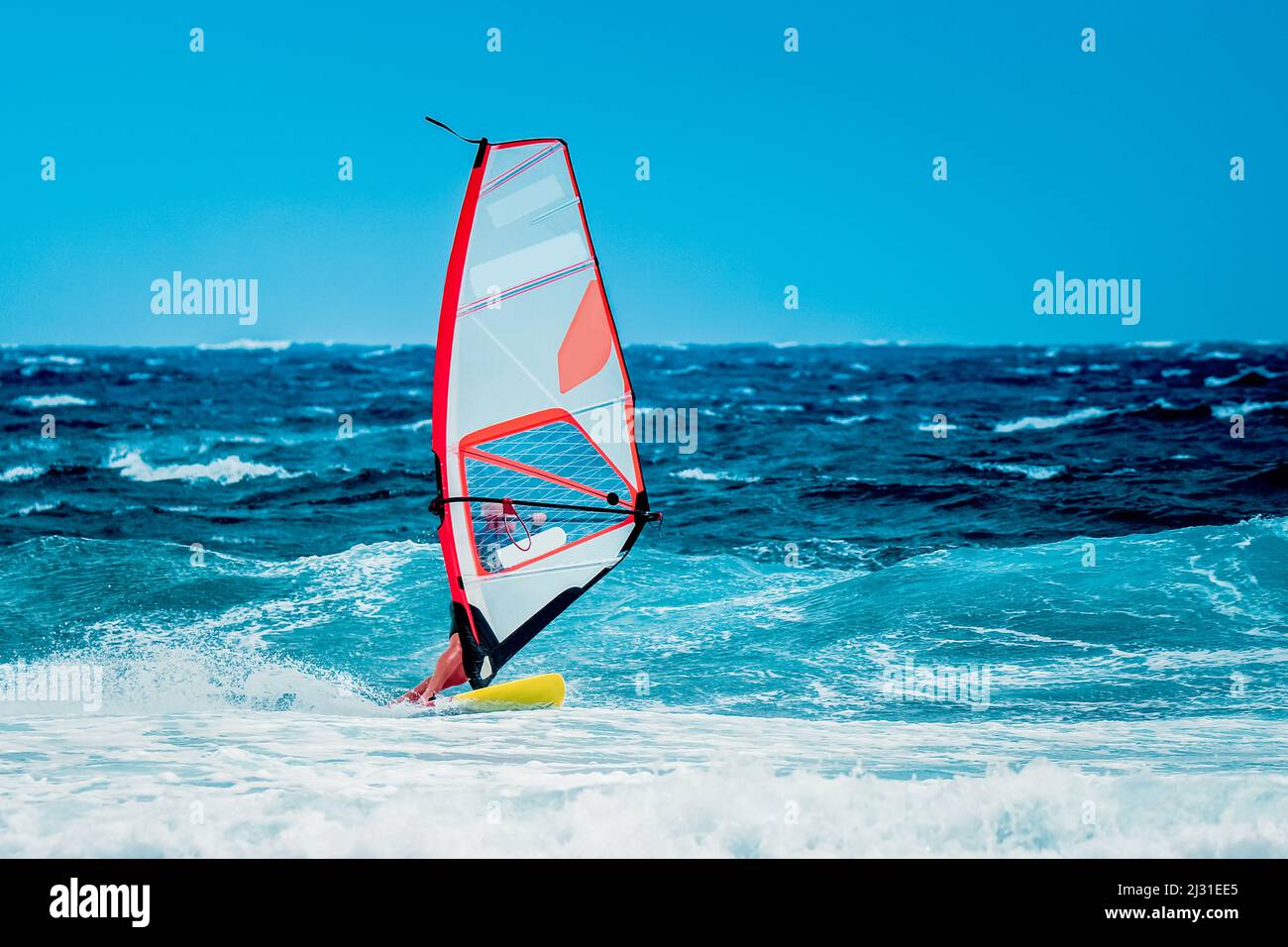 summer sport: windsurfer riding among waves on the blue ocean Stock Photo