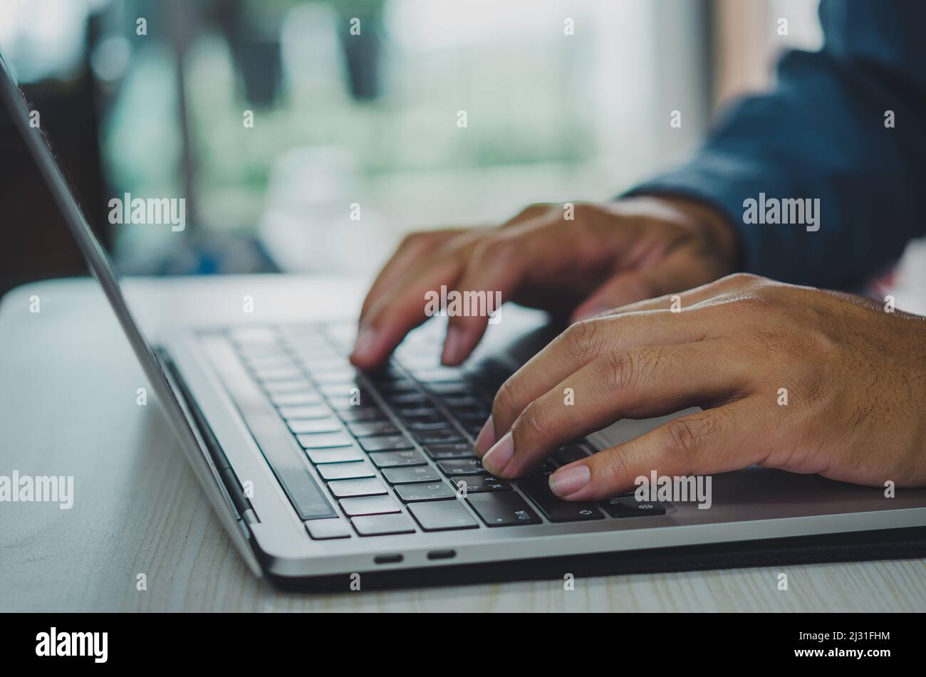 man using computer laptop searching internet, sending sms, using text messenger or online banking. Stock Photo