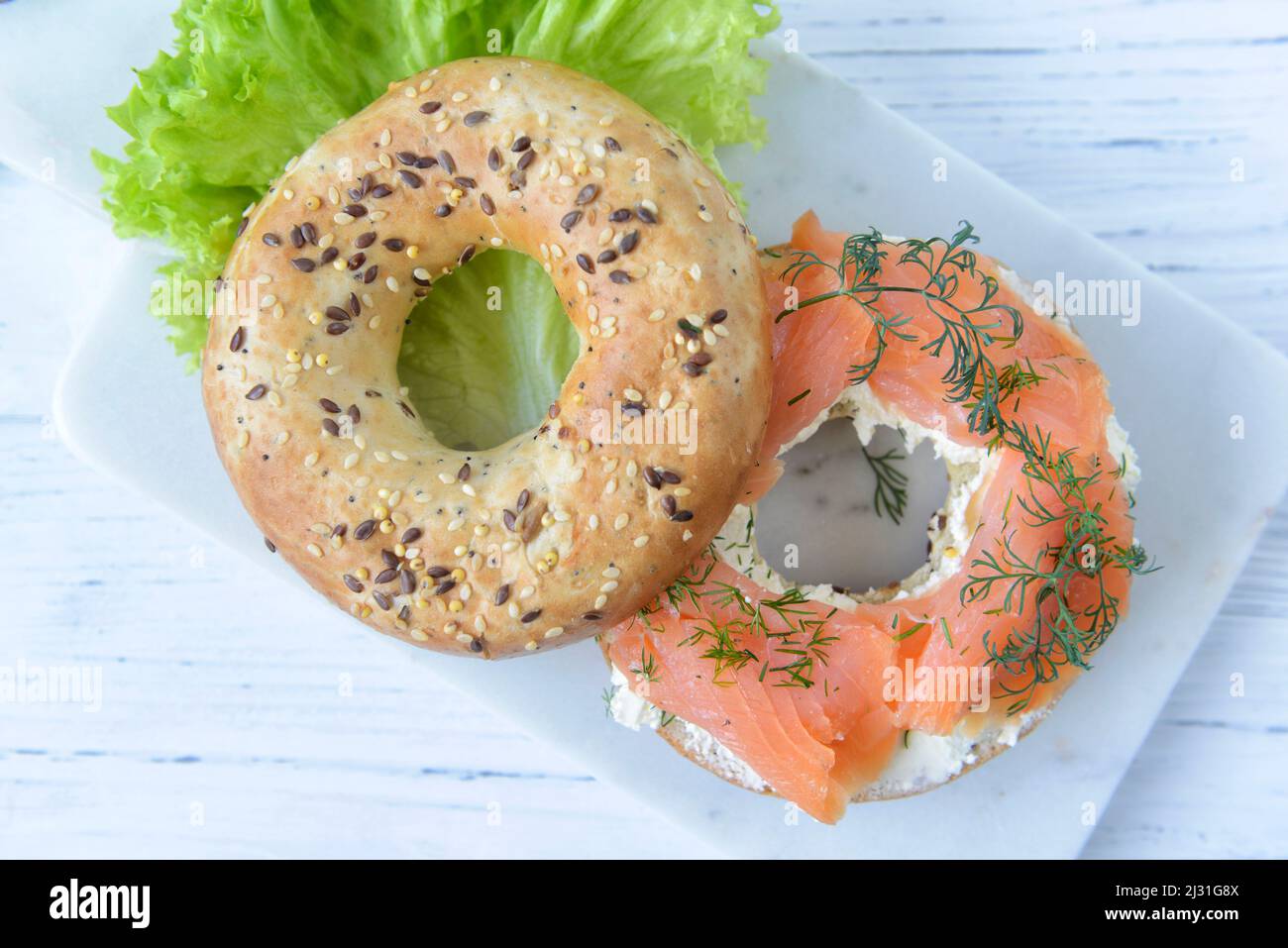 Fresh multigrain bagel with cream cheese, salmon slices, dill and green