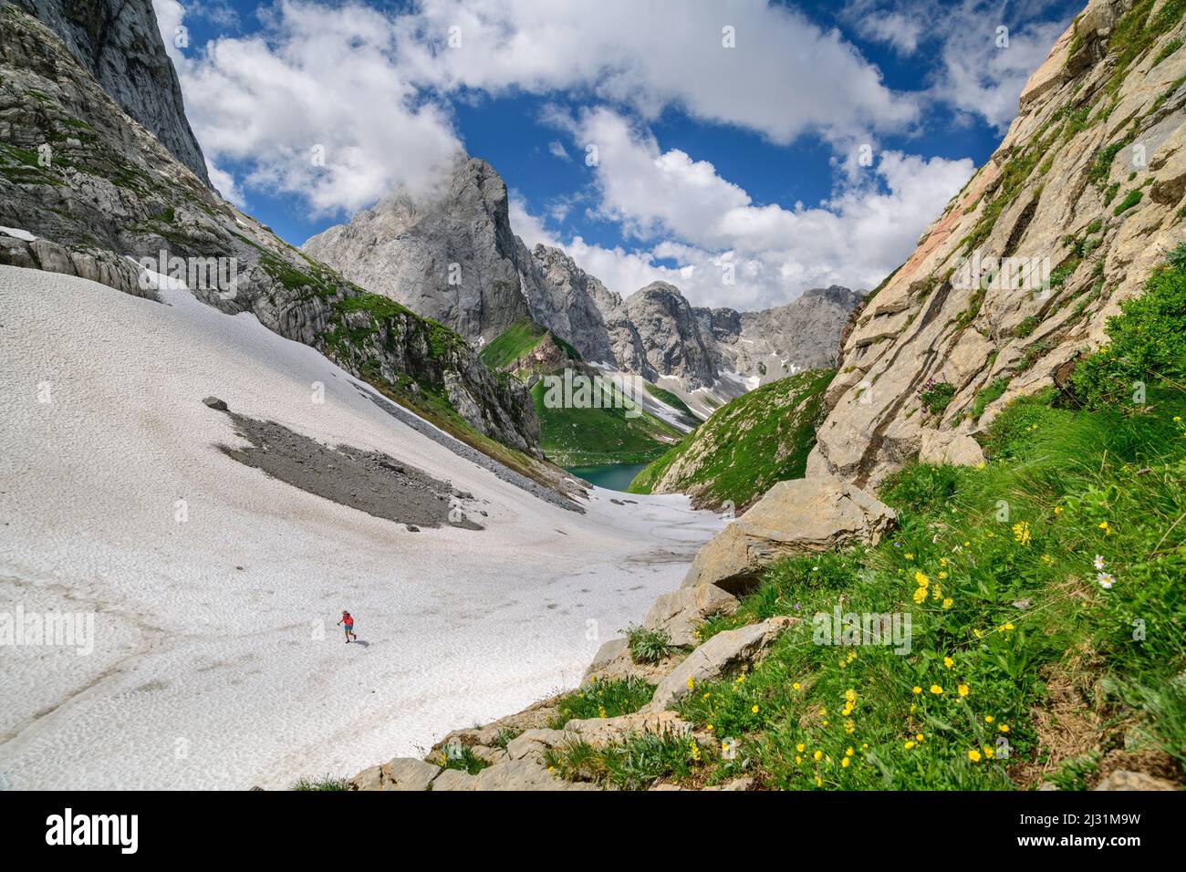 Hiking person ascends over snow field to Valentintörl, Valentintörl, Carnic Alps, Carinthia, Austria Stock Photo