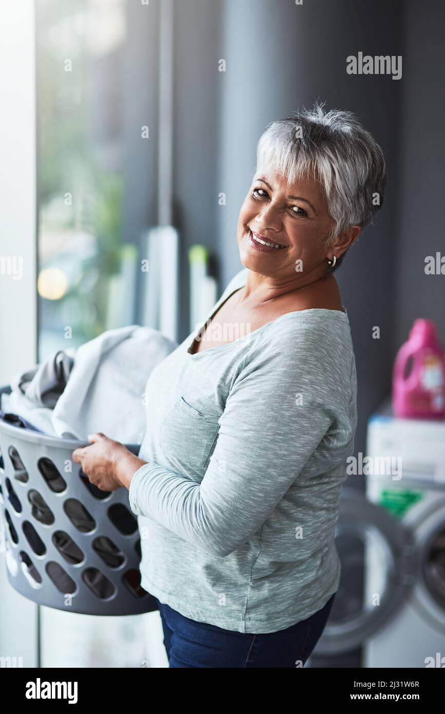 You can call me the authority on all things laundry. Portrait of a mature woman doing laundry at home. Stock Photo