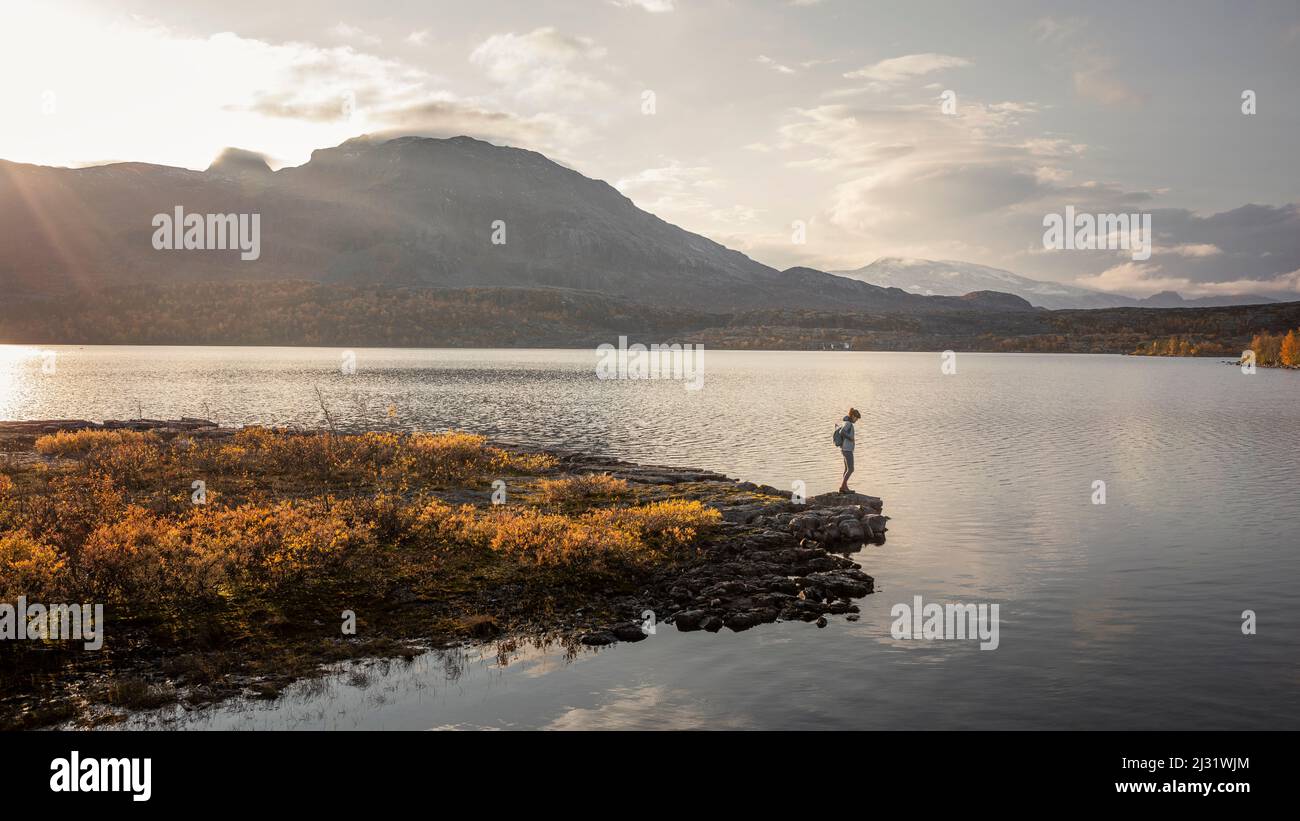 Woman in landscape with mountains and lake in Stora Sjöfallet National Park in autumn in Lapland in Sweden Stock Photo