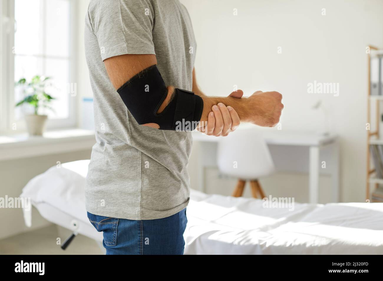 Bandage on elbow of unknown man that he wears to restore and relieve joint pain. Stock Photo