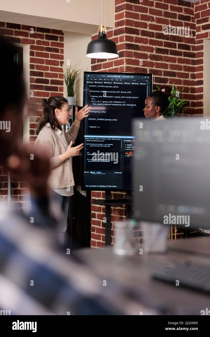 Multiethnic developer team talking about rising number of system security breaches. Tech engineers trying to solve storage space problem by using advanced artificial intelligence. Stock Photo