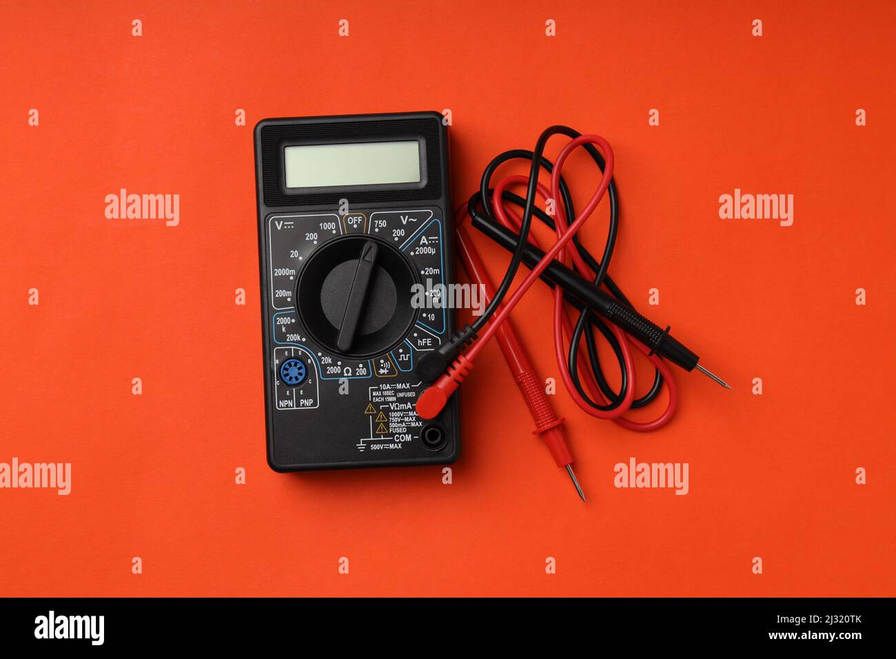 Black multimeter on orange background, top view Stock Photo