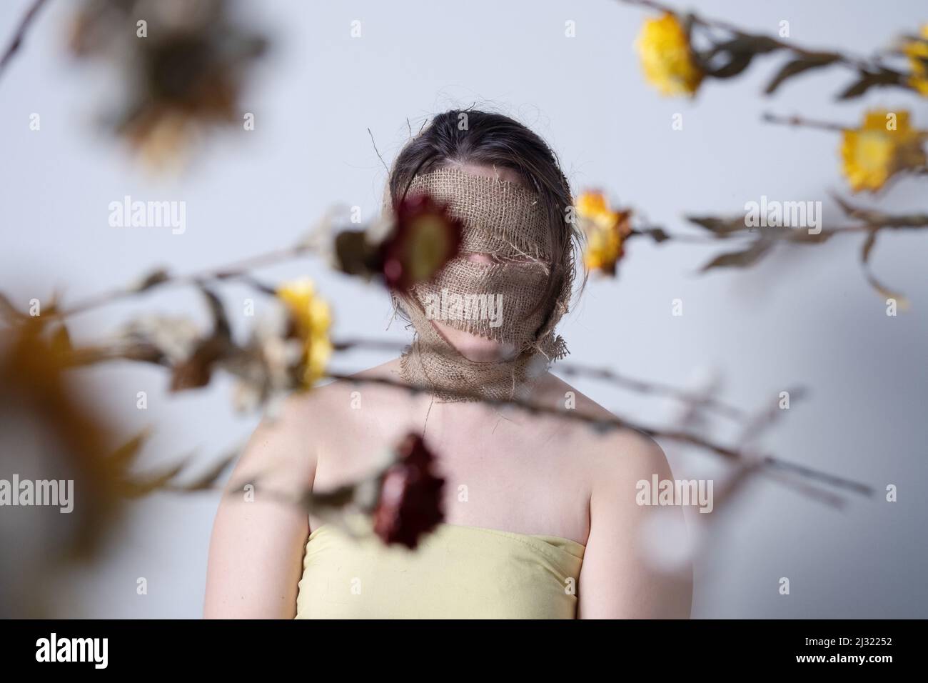 Female figure face wrapped in burlap, symbolizing shedding skin and