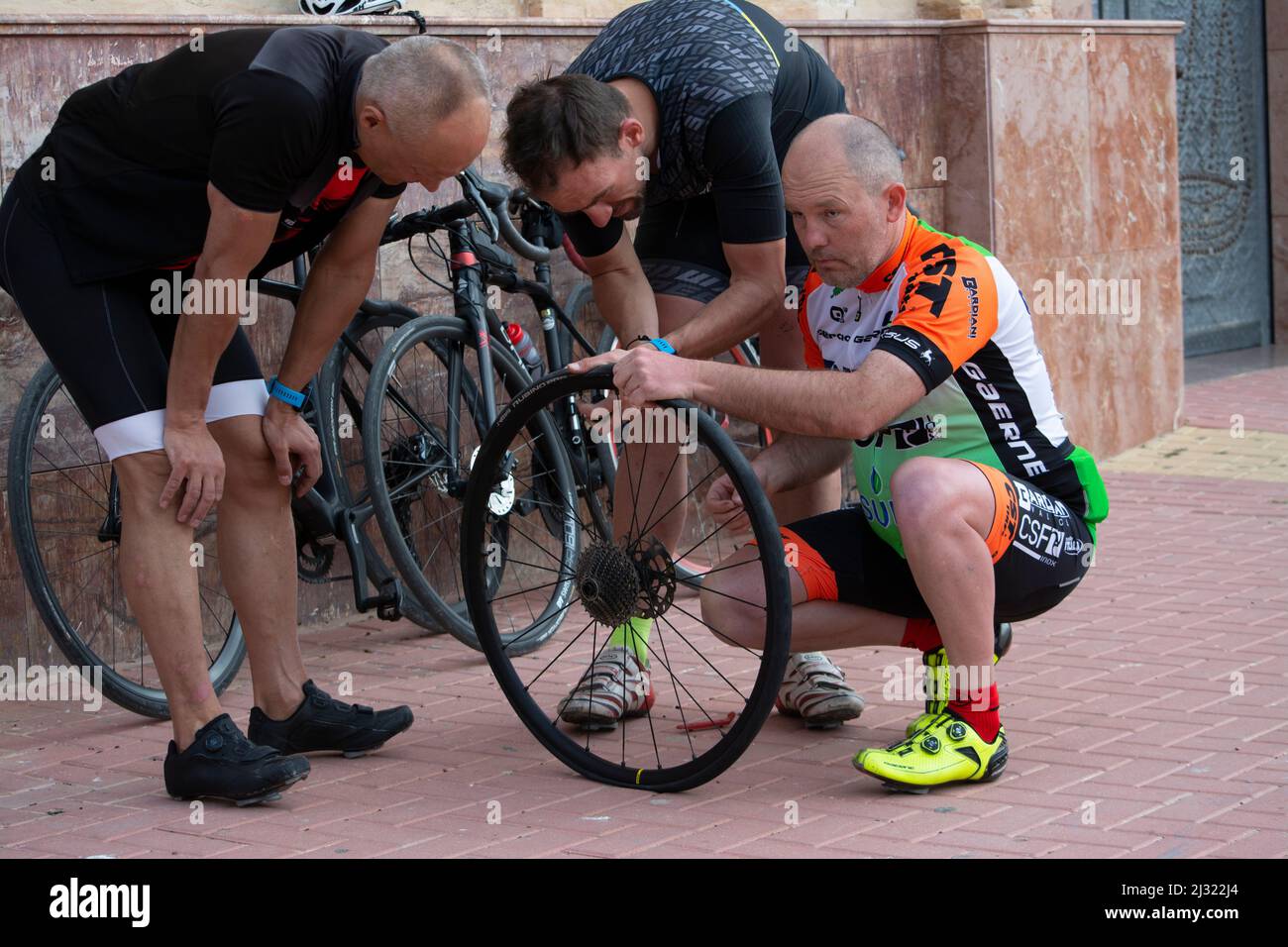 Three cyclists repairing a the puncture of a bike tyre Stock Photo