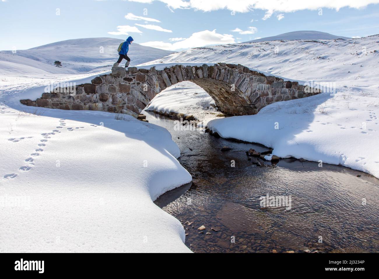 Walkers on stone bridge, Old Miltary Road in snow, Corgarff, Lecht Road, Cairngorms, Highlands, Aberdeenshire, Scotland, UK Stock Photo