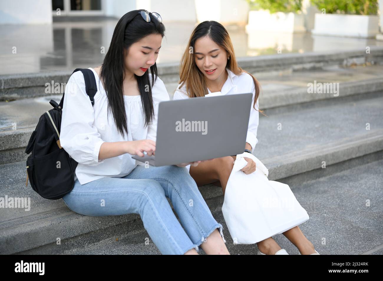 Two Asian female college student sitting on the stairs, working and ...