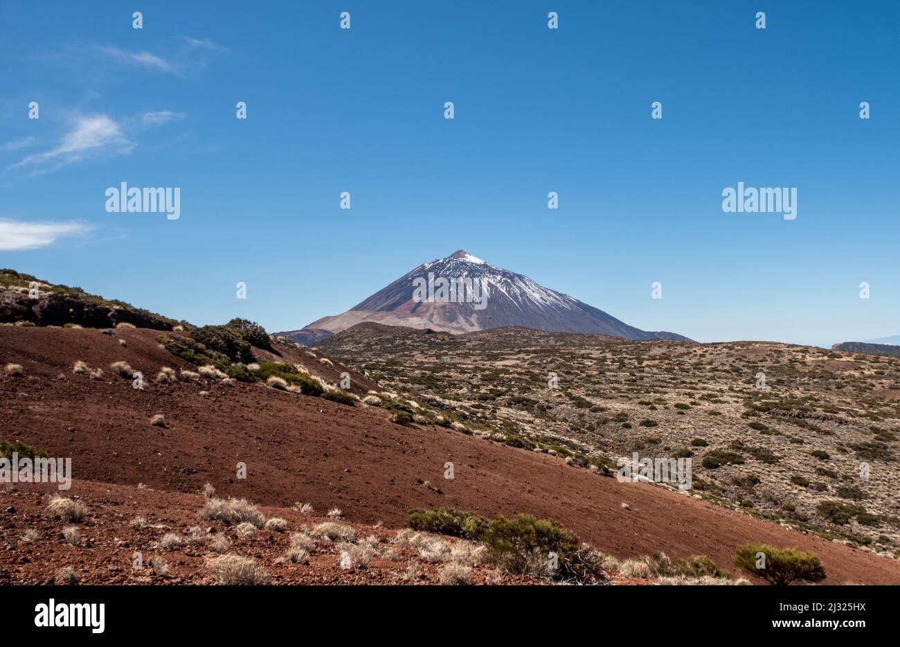 Teide National Park Tenerife with snow capped volcano behind red ground. Stock Photo