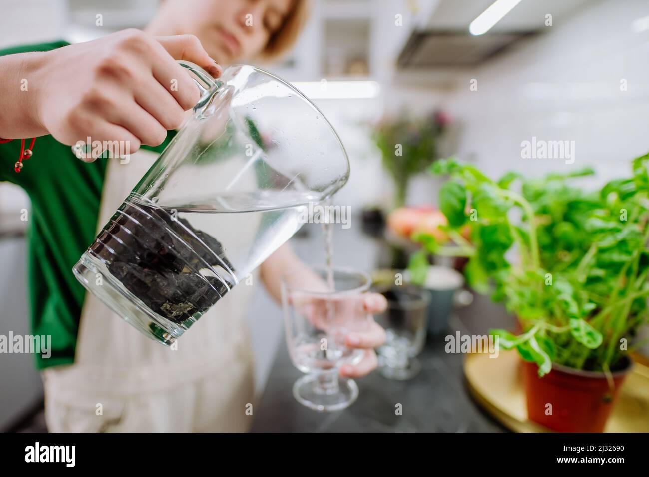 Girl pouring water from jar with shungite stones Stock Photo