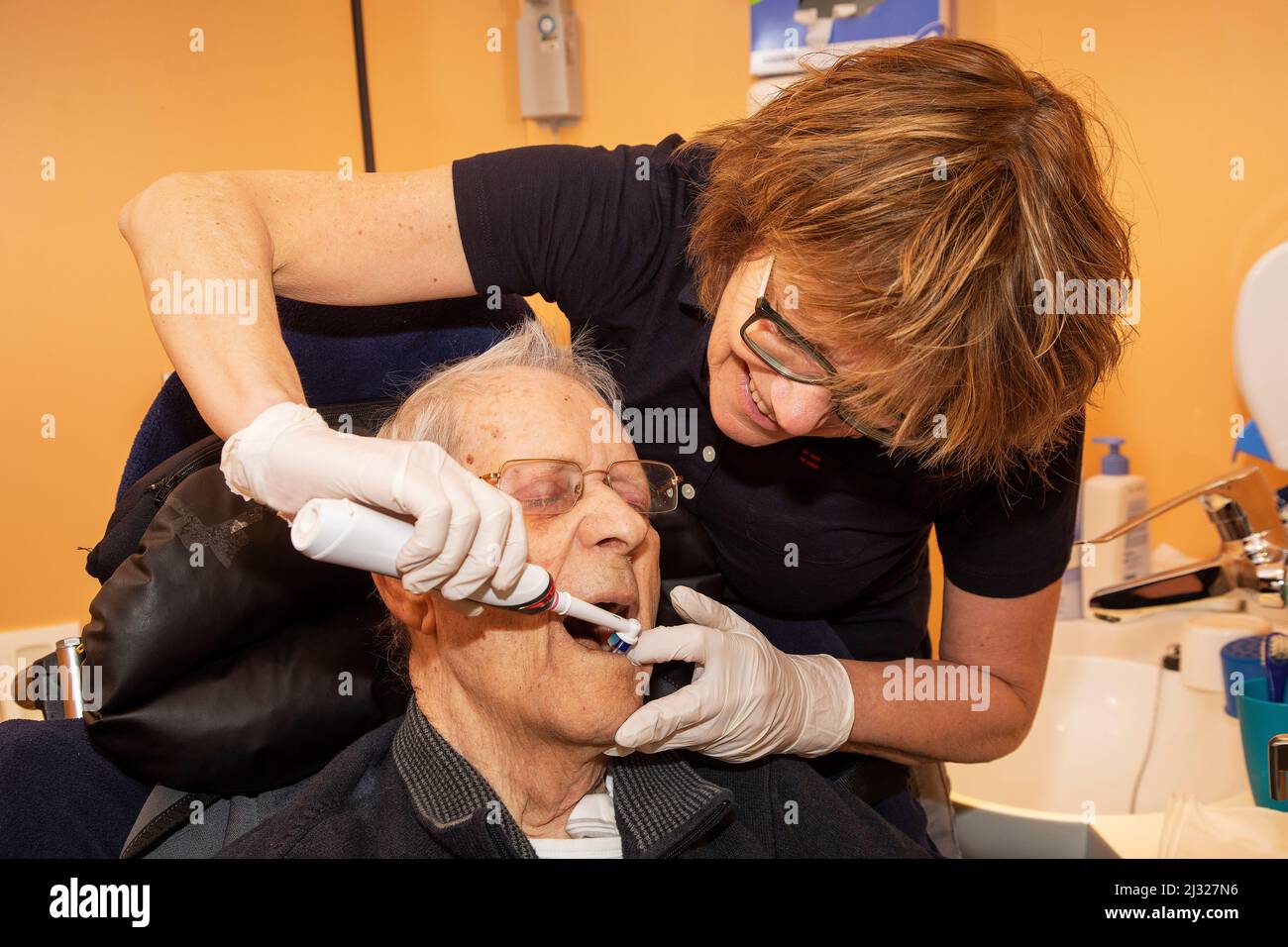 Netherlands, Gendt - Nurse in a care home for elderly is brushing the teeth of a resident. Stock Photo