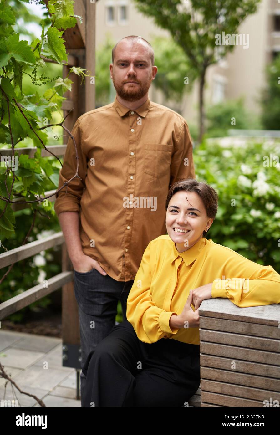 Young confident business colleagues standing outside office building looking forward. Team of finance managers, economists or real estate agents in casual clothes outdoors. High quality image Stock Photo