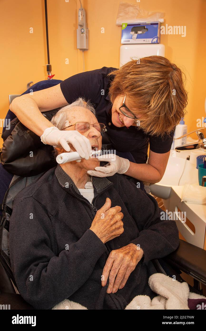 Netherlands, Gendt - Nurse in a care home for elderly is brushing the teeth of a resident. Stock Photo