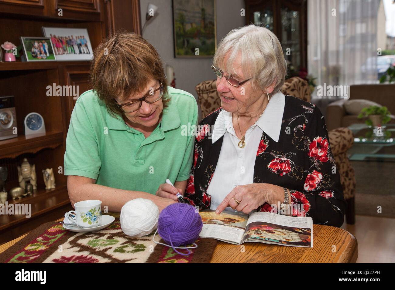 Netherlands, nurse of a home care organisation at home of a client, discussing how to solve the problems from the client. Stock Photo