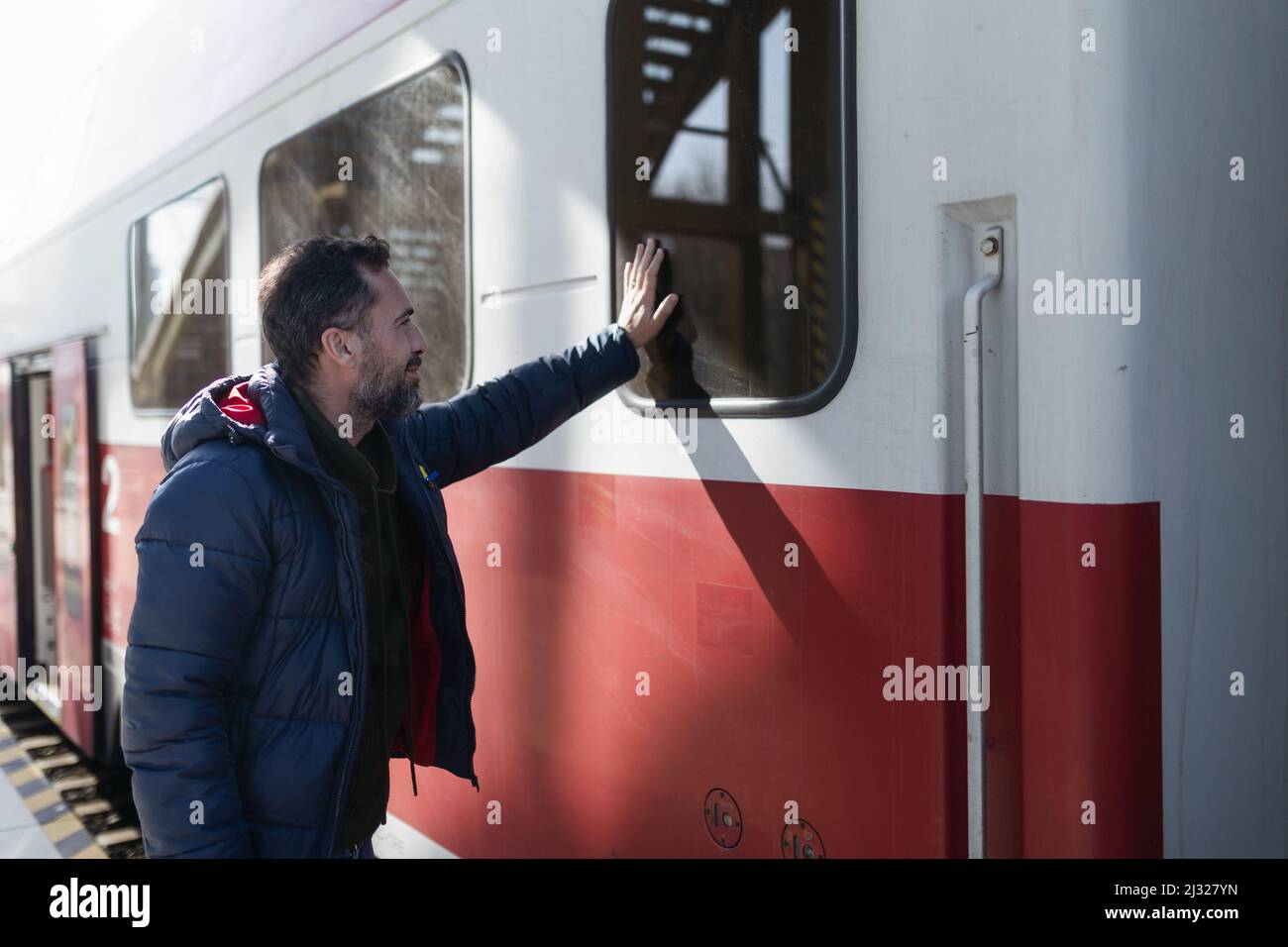 Ukrainian man saying good bye and waving to his family in train leaving Ukraine due to Russian invasion in Ukraine. Stock Photo