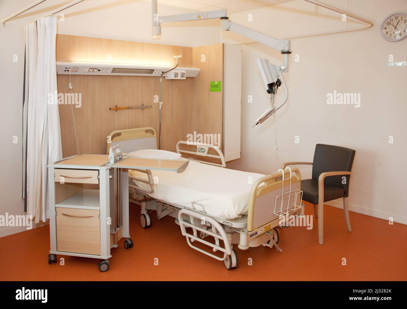 Netherlands, an hospital room with a bed, chair and pedestal cupboard Stock Photo
