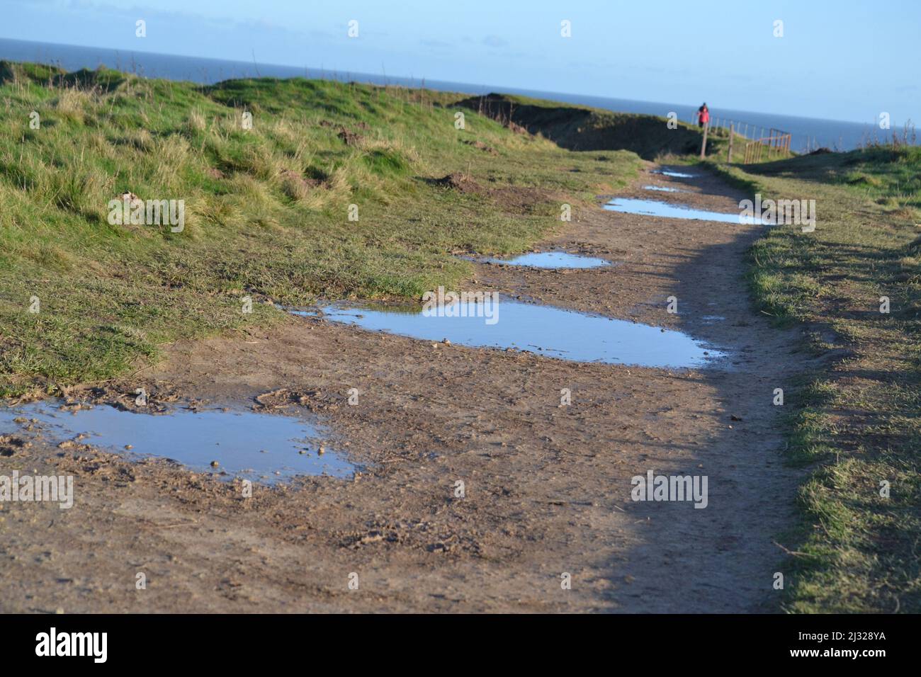 Puddles On Footpath Along Filey Brigg - Bright Sunny Winters Day - Blue Sky Reflecting In Puddles - North Yorkshire - UK Stock Photo