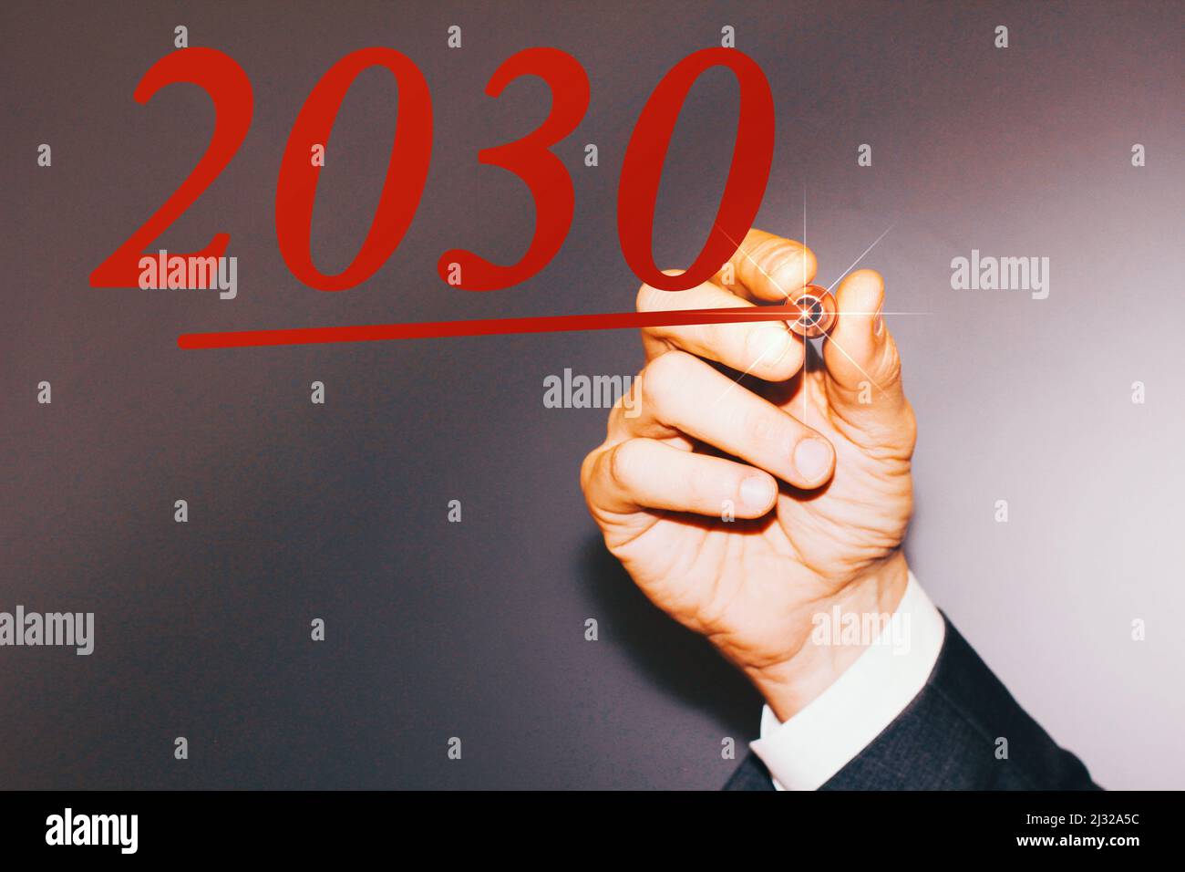 Hand of a business man writing the year “2030” with a red pen Stock ...