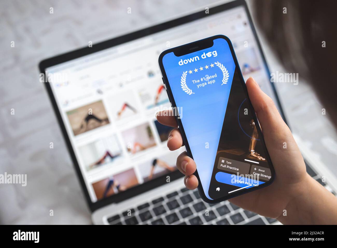 Young woman use Yoga Down Dog mobile app logo on mobile phone screen, close-up icon Stock Photo