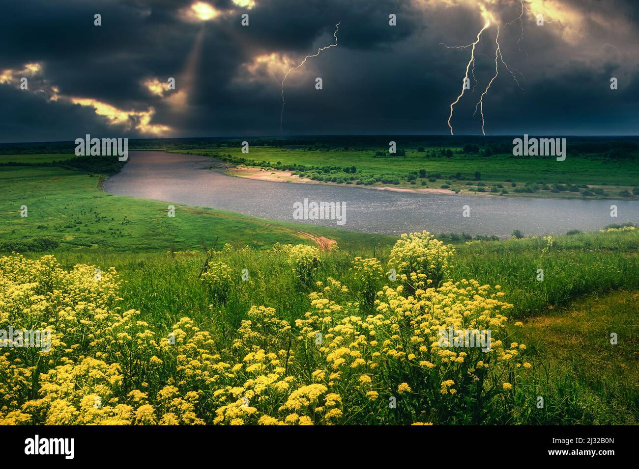 summer thunderstorm over the lightning river top view yellow meadow of flowers on the hill Stock Photo