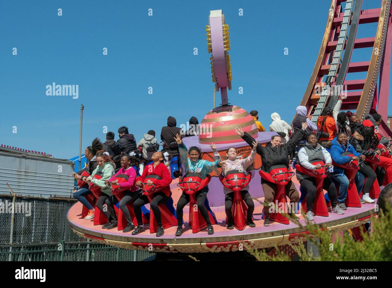 Young women enjoy the Electro Spin ride in Luna Park on an early spring day. Coney Island, Brooklyn, New York, 2022. Stock Photo