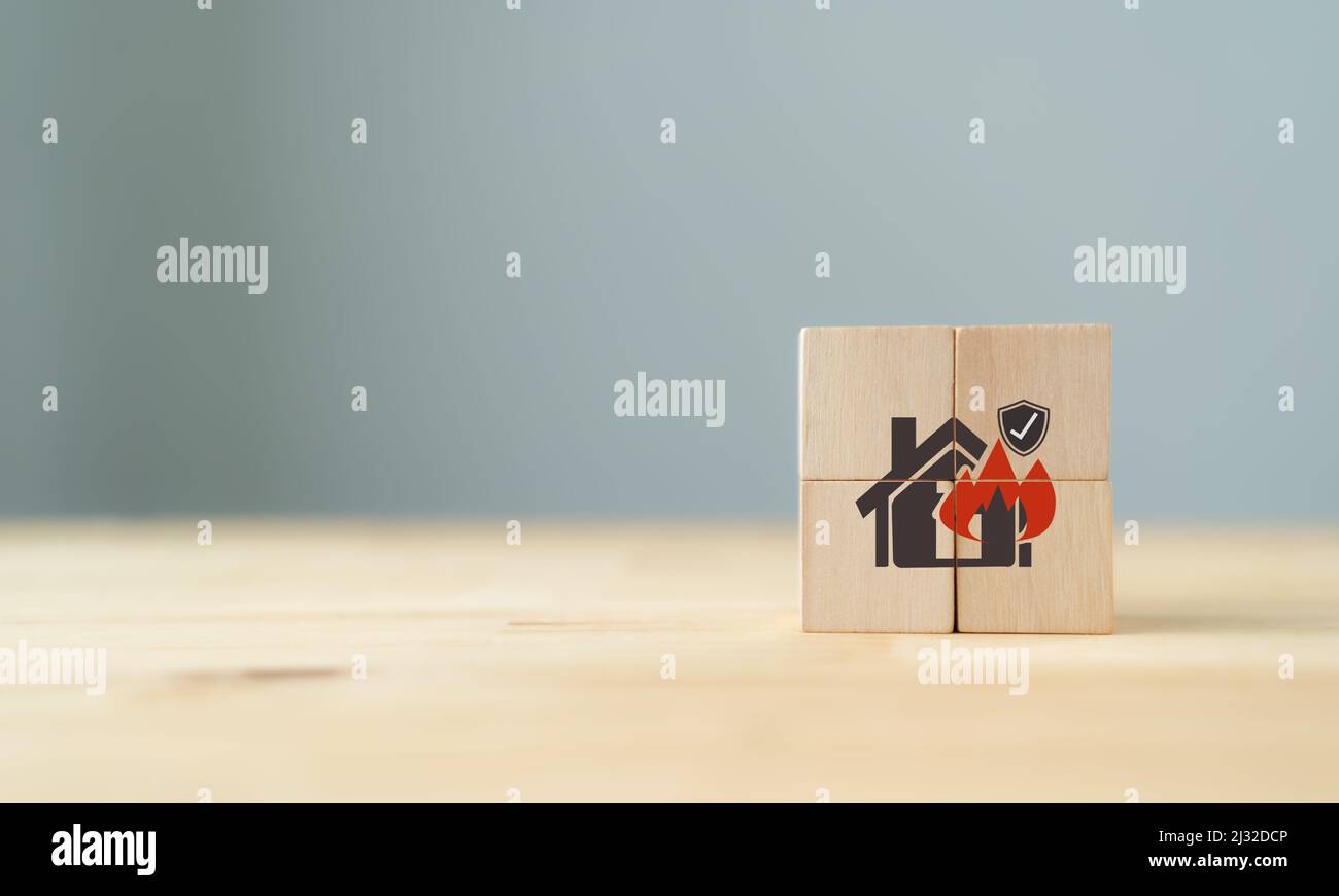 House building in flames. Insurance concept. Financial security, safety, damage, accident prevention. Wooden cubes with fire insurance icon on grey ba Stock Photo