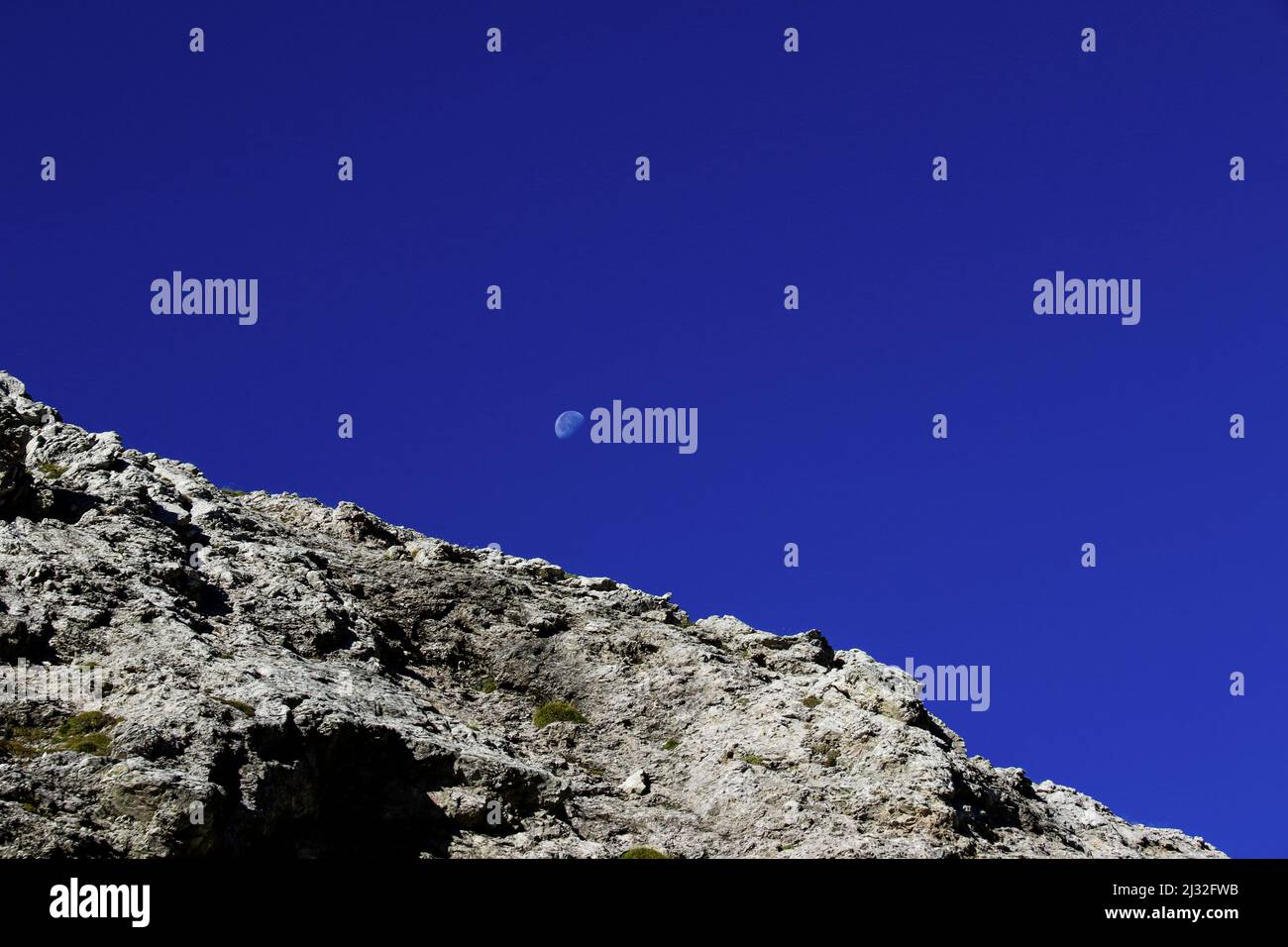 Moon rising behind mountain, north Italy Stock Photo
