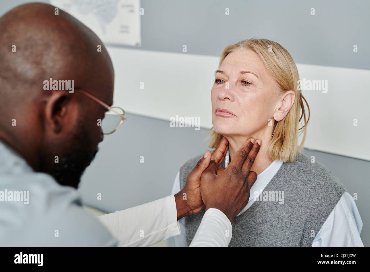 Mature blond female patient having checkup of her thyroid glands by