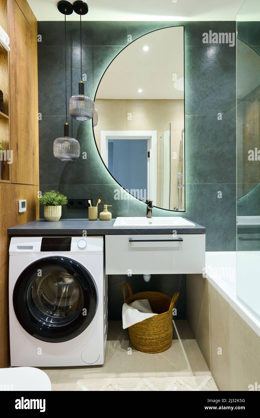 Two glass lamps hanging over sink and bodycare items on washing machine in  bathroom inside contemporary apartment Stock Photo - Alamy
