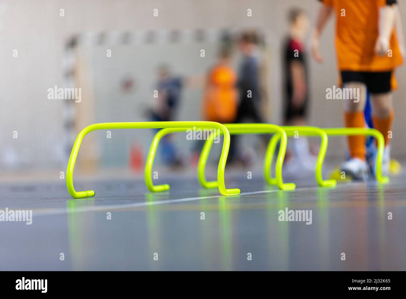 Indoor sports training with yellow hurdles. Young boy running and