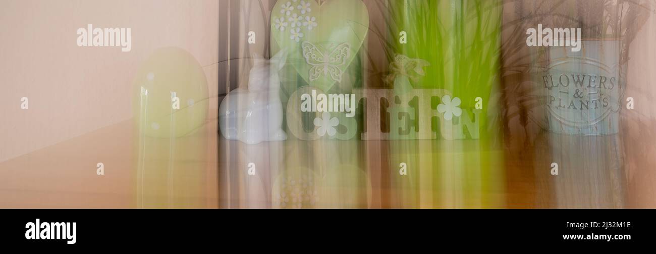 Banner with different Easter decorations created by a blur effect. The text on the sign is German for Easter. Stock Photo